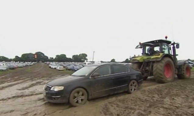 Трактор вытаскивает машину из грязи